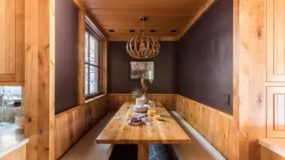 a dining room with a wooden table and a chandelier at Hunter by AvantStay Award-Winning Riverfront Cabin 5 Minutes from Palisades in Olympic Valley