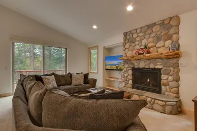 a living room with a couch and a stone fireplace at Lukins Lodge By The Lake Hot Tub in South Lake Tahoe