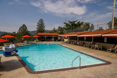 a large swimming pool with tables and umbrellas at Pet Friendly Grizzly Blair Lodge Cabin in Groveland