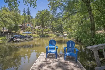 two blue chairs sitting on a dock next to a river at Lakefront Cozy Cabin on the Cove in Groveland