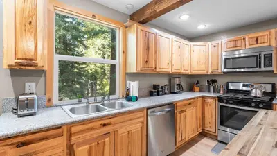 a kitchen with wooden cabinets and a sink and a window at Sweet Pine Deck Hot Tub Cozy Modern Interior Close to Ski Resort in Pomins
