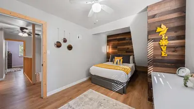 a bedroom with a bed and a wooden wall at Sweet Pine Deck Hot Tub Cozy Modern Interior Close to Ski Resort in Pomins