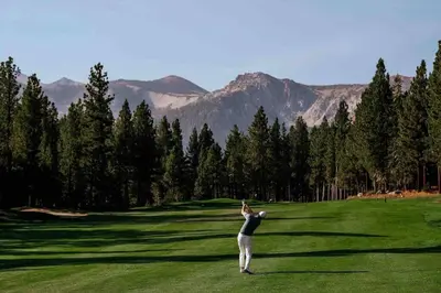 a woman standing on a golf course with her arm in the air at Top rated cabin w/spa Walk to the Village & Golf in Mammoth Lakes
