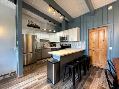 a kitchen with white cabinets and a counter with stools at Top rated cabin w/spa Walk to the Village & Golf in Mammoth Lakes