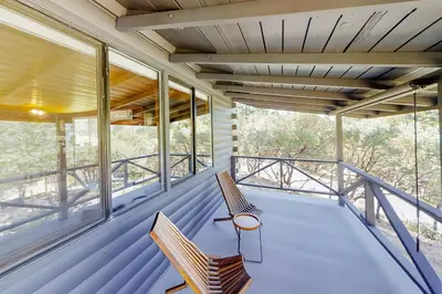 two chairs sitting on a porch with windows at Sugar Pine Log Cabin in Oakhurst