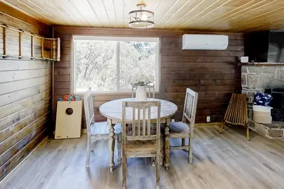 a dining room with a table and chairs and a window at Sugar Pine Log Cabin in Oakhurst