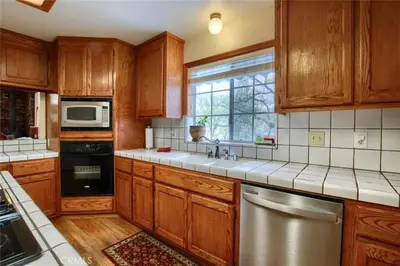 a kitchen with wooden cabinets and a stainless steel dishwasher at Beautiful Pet-Friendly Spacious Lodge near Yosemite & Lakes 12 Beds 6 BR up to 16 people in Oakhurst