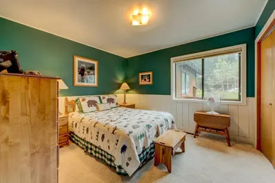 a bedroom with green walls and a bed and a window at Grizzly Cabin in Truckee