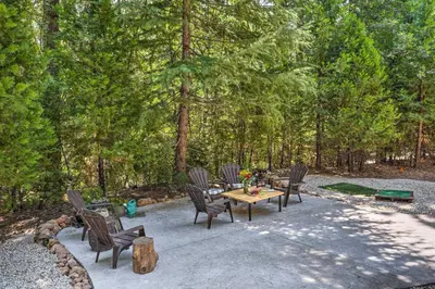 a patio with a table and chairs in the woods at 1 Mi to Jenkinson Lake Apples Chalet with Deck in Pollock Pines
