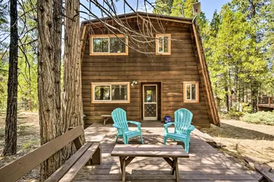 a cabin in the woods with two blue chairs at Charming Pinecrest Cabin with Private Deck in Strawberry