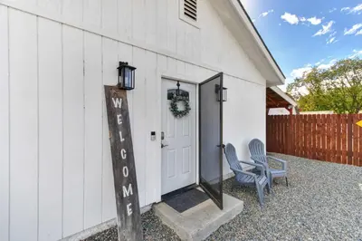 a white barn with a door and a chair at Country Charmer Single Story Cottage Pet Friendly in Loomis