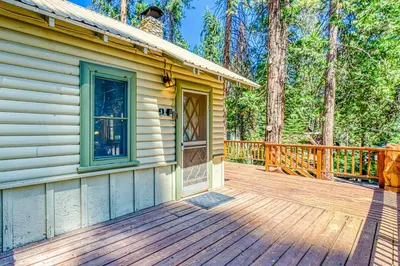 a home with a wooden deck with a house at Alpine Cottage in Shaver Lake