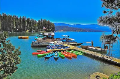 a group of kayaks parked at a dock on a lake at Alpine Cottage in Shaver Lake