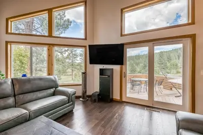 a living room with a couch and a tv and windows at Basque in Nature in Truckee