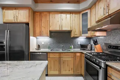 a kitchen with wooden cabinets and stainless steel appliances at Modern Condo - EV Plug In - SM 301 in Bear Valley