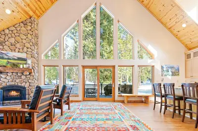 a living room with a fireplace and a stone wall at Oso Lodge in Yosemite West