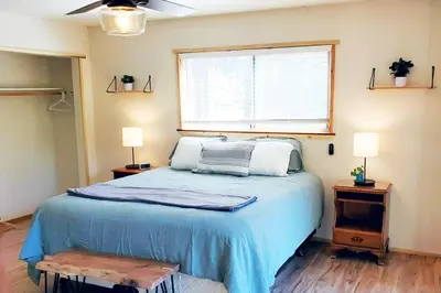 a bedroom with a bed with a blue blanket and a window at Redwood Retreat, Mountains, Adventure and Nature in Ponderosa