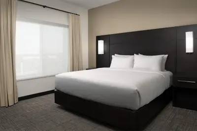 a large bed in a hotel room with a large window at Residence Inn by Marriott Fresno Clovis in Clovis