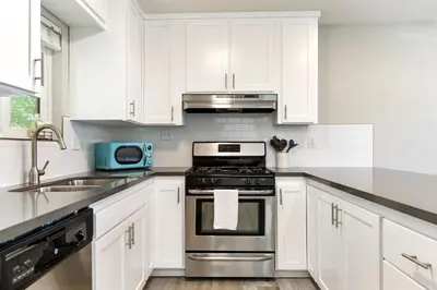 a kitchen with white cabinets and a stove top oven at Fully Renovated 4 Bedroom Home with Pool! in Roseville