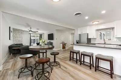 a kitchen and living room with a table and stools at Fully Renovated 4 Bedroom Home with Pool! in Roseville