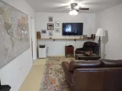 a living room with a couch and a cat sitting in a chair at Cozy Cottage in Miramonte