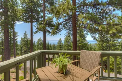 a wooden table and chair on a deck with trees at Casa Azul in Incline Village