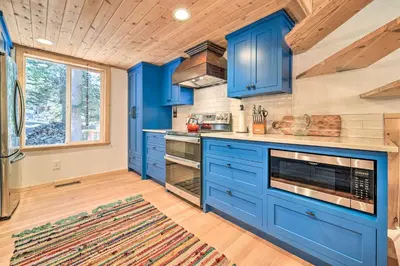 a kitchen with blue cabinets and a wooden ceiling at Waterfront Echo Lake Cabin with Deck, Mtn Views in Twin Bridges