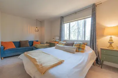 a bedroom with a large bed and a blue couch at Sweet Arnold Cabin in Arnold