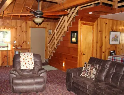 a living room with two leather chairs and a ceiling fan at Rustic Chapparal Cabin at Bass Lake Heights in Oakhurst
