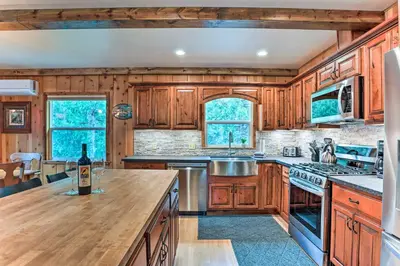 a kitchen with wooden cabinets and a counter with a bottle of wine at Rustic Oakhurst Retreat Less Than 4 Mi to Bass Lake! in Oakhurst