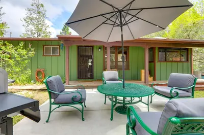 a patio with chairs and a table with an umbrella at 1 Mi to Lake Hot Tub Haven in Pollock Pines! in Pollock Pines