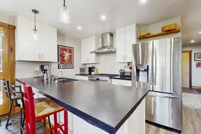 a kitchen with white cabinets and a stainless steel refrigerator at Coyote Fork Escape in Truckee