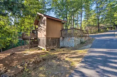 a house with a fence next to a road at Deck and Grill Mtn Haven in Stanislaus Natl Forest in Arnold