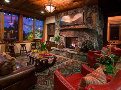 a living room with a stone fireplace and a table at Cedar Glen Lodge in Tahoe Vista