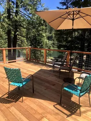a wooden deck with chairs and an umbrella at Lakeside BLS Retreat near Big Trees & Bear Valley in Arnold