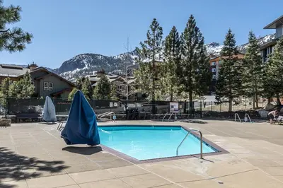 a swimming pool with a blue umbrella in a courtyard at Ski in Ski Out Juniper Springs Lodge #351 Luxury Slope-side 2 Bedrm 2 Bath End Unit! in Mammoth Lakes