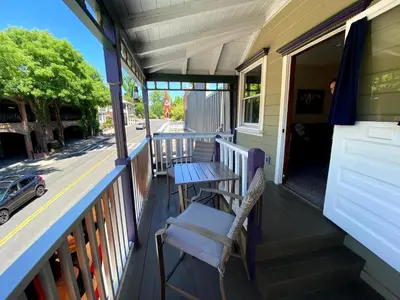 a porch with a table and a chair on it at Historic Washington St Balcony in Sonora