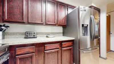 a kitchen with wooden cabinets and a stainless steel refrigerator at Aspen Creek #115 condo in Mammoth Lakes