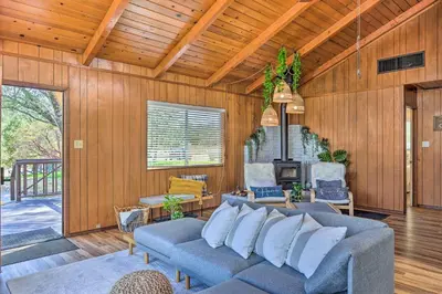 a living room with a blue couch and wooden walls at Lovely Oakhurst Cabin with Deck and Mtn Views! in Oakhurst