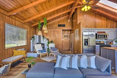 a living room with a couch and a kitchen at Lovely Oakhurst Cabin with Deck and Mtn Views! in Oakhurst