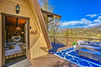 a porch with a couch and a table on a deck at Lovely Oakhurst Cabin with Deck and Mtn Views! in Oakhurst