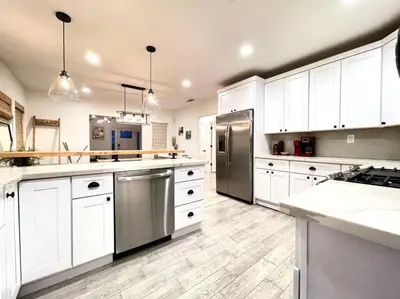 a large kitchen with white cabinets and stainless steel appliances at King Bed-Private Yard-Driveway Parking in Sacramento