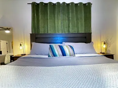 a bedroom with a large bed with a green curtain at King Bed-Private Yard-Driveway Parking in Sacramento