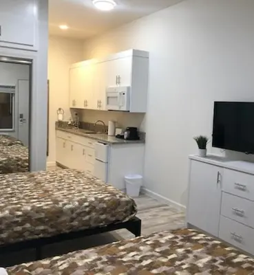 a hotel room with two beds and a kitchen at Villa Alamari Inn and Suites in Kerman