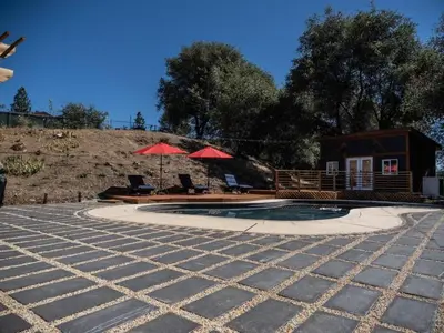 a house with a swimming pool and a house with red umbrellas at Pool! Quite, Private, remodeled home on the hill in Placerville