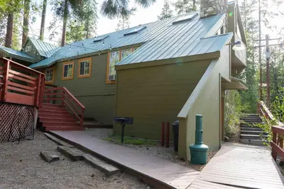a house with a deck and stairs in the woods at Bear Cave- Pet Friendly Suite in Shaver Lake in Shaver Lake