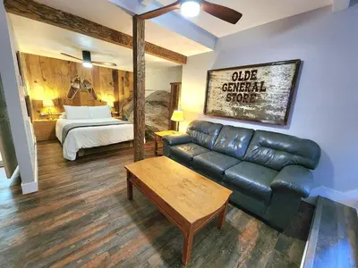 a living room with a leather couch and a bed at Bear Cave- Pet Friendly Suite in Shaver Lake in Shaver Lake