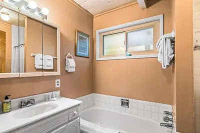 a bathroom with a tub and a sink and a mirror at Jug Handle Hideaway in Arnold