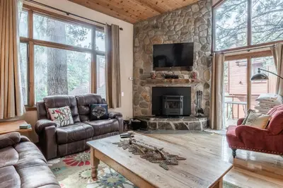 a living room with a stone wall with a fireplace at Updated 2 Bedroom and Loft 2 Full Bathroom Woodlands #51Just Steps to Shuttle Close to Golf Course in Mammoth Lakes