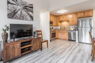 a kitchen with wooden cabinets and a flat screen tv at Summit #256 - Top Floor Summit 1 Bedrm 1 Bathrm Condo Just steps too Little Eagle Lodge Sleeps 4 in Mammoth Lakes